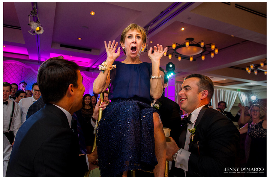 The groom's mother is shocked as she is lifted into the air as a Jewish Wedding tradition.