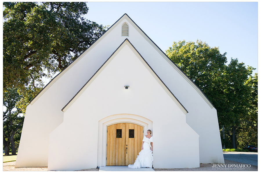 The bride poses in front of the doors of the white non-denominational chapel on the estate grounds.