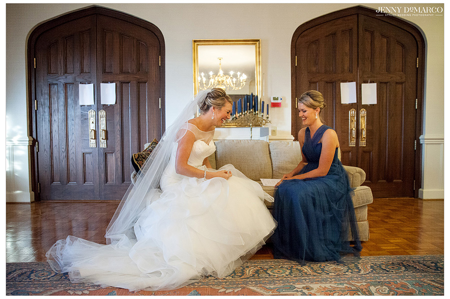 Gorgeous bride sits with one of her bridesmaids in beautiful church before marrying the man of her dreams.