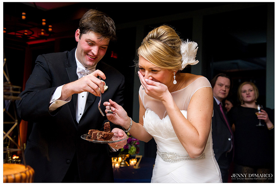 Bride laughs as her and the groom enjoy their wedding cake. 