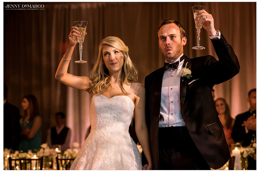 The bride and groom raise their glasses as family and friends begin their toasts.