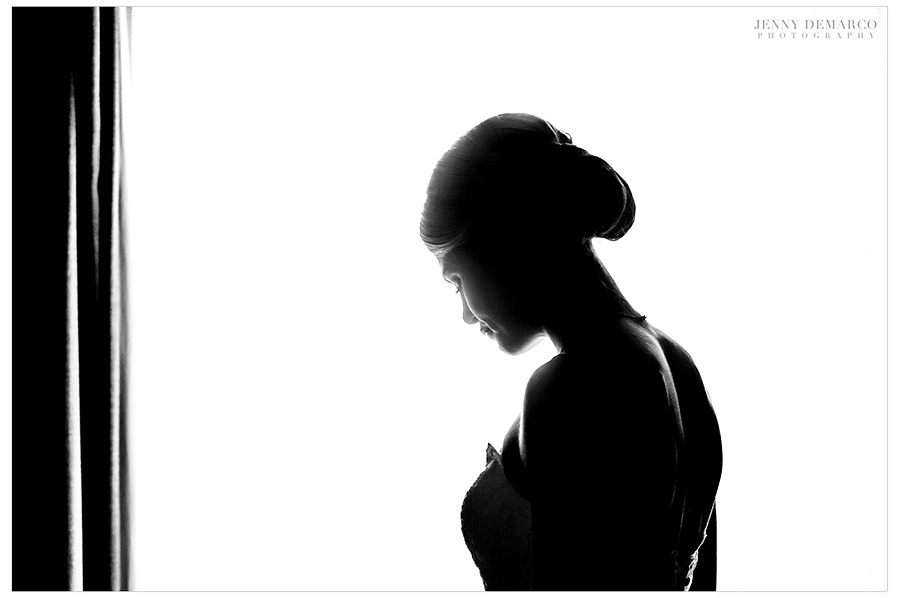 Black and white silhouette of the bride in front of the lighted window. 