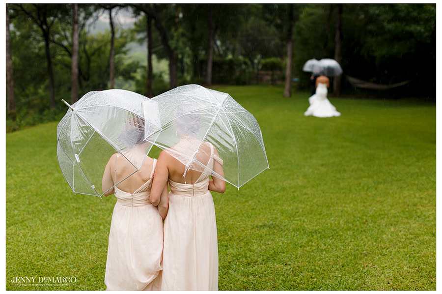 Bridesmaids watch bride groom reveal from afar outside in rain 