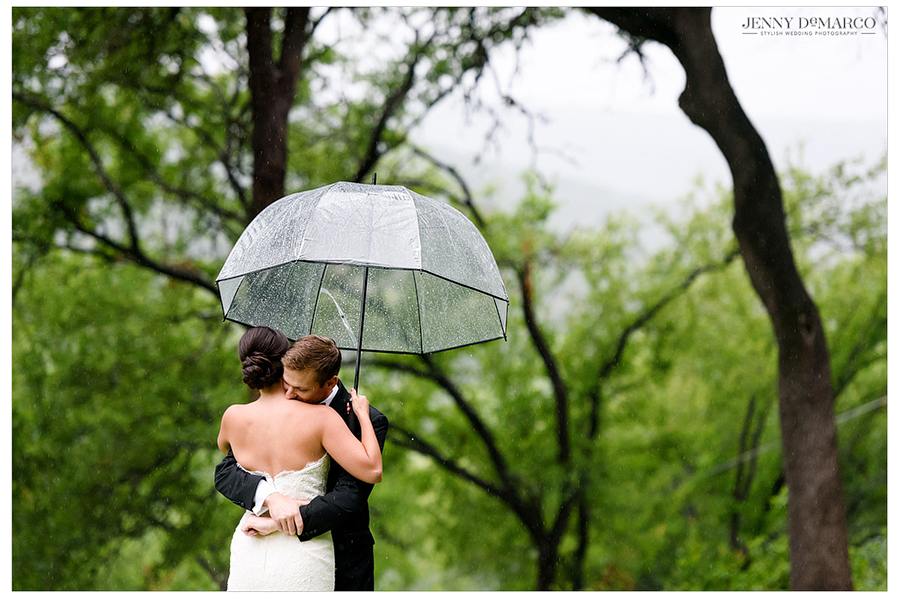 Groom passionately hugs bride under umbrella after first look 