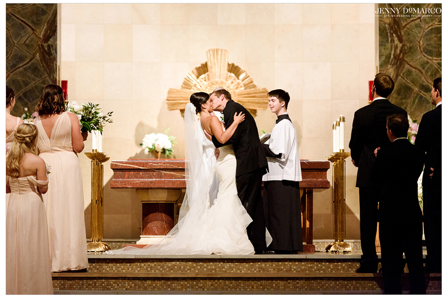 Bride and groom passionately share their first kiss on the altar