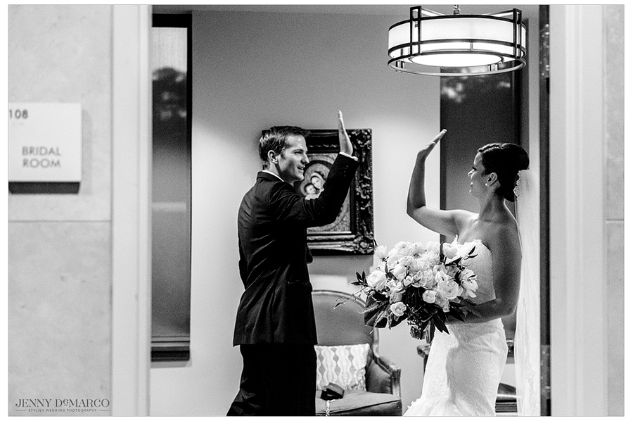 Bride and groom high five just after getting married in bridal room 