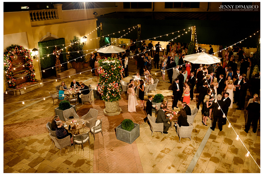 Reception party birds eye view, with string lights above guests eating and drinking 