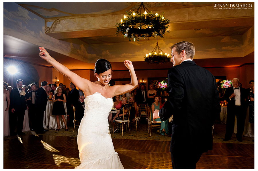 Bride throws her arms up as she dances for the first time with her husband