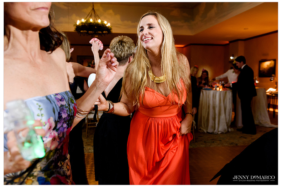 Guest in bright orange dress dancing at reception 