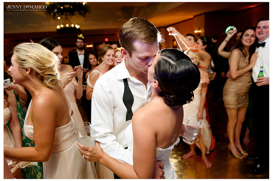Bride and groom share an intimate kiss on a very busy dance floor 