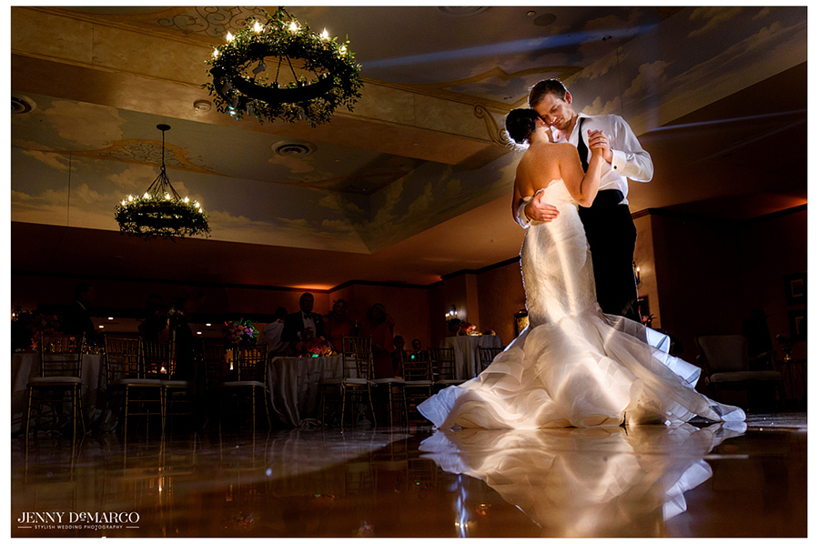 Bride and Groom share a dance on an empty dance floor, beautifully lit underneath dress 