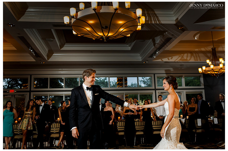 The bride and groom share their first dance as friends, family, and guests gather to watch.