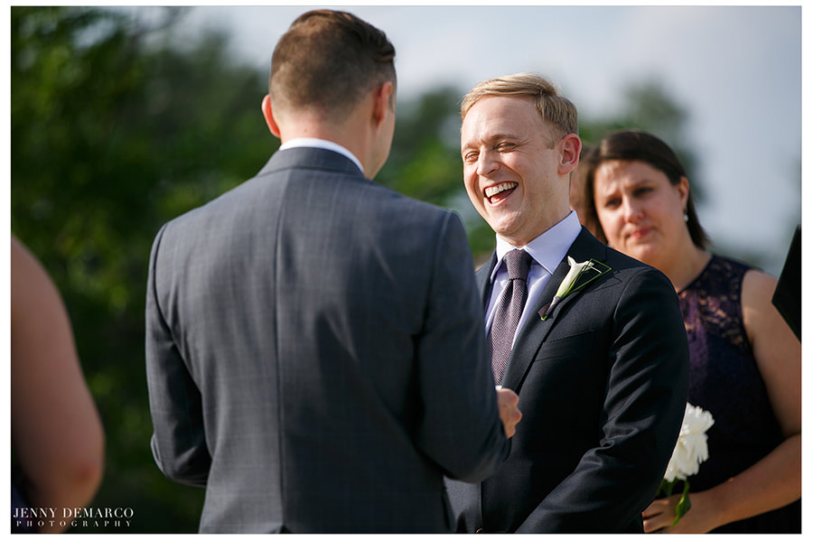 One groom laughs during wedding ceremony.