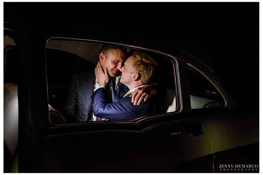 Grooms embrace in the back seat of their getaway car.