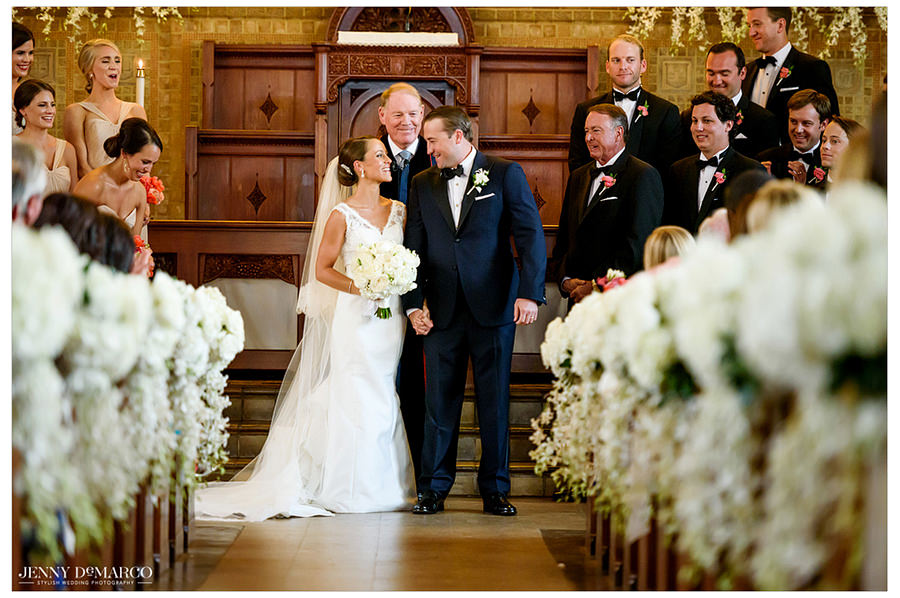 The newlyweds smile at each other at the front of the church before walking down the aisle to exit the church.