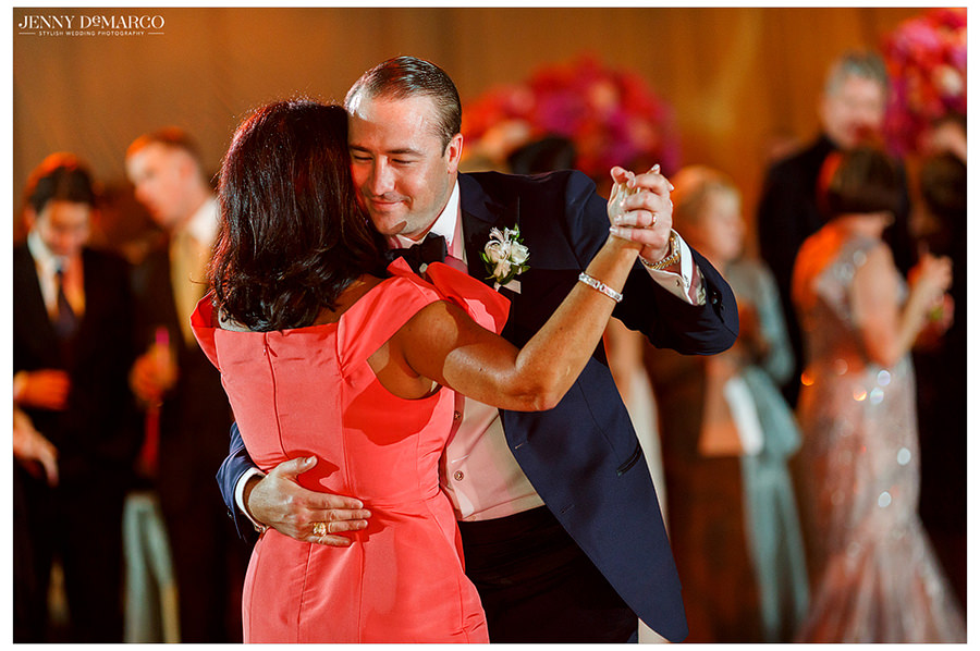The groom smiles as he dances with the mother of the bride.