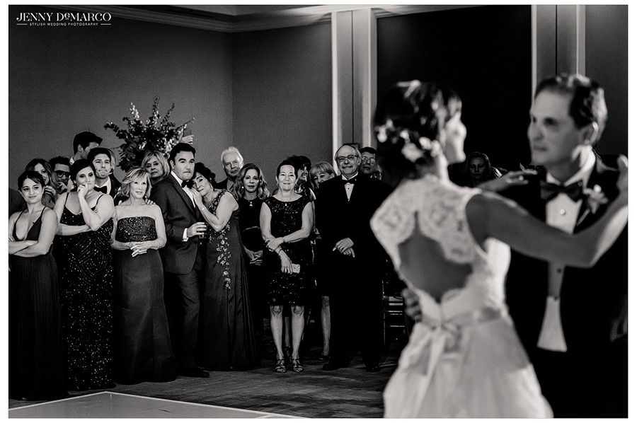 With the bride and her father out of focus, the guests watch the sweet moment as they share their father daughter dance.