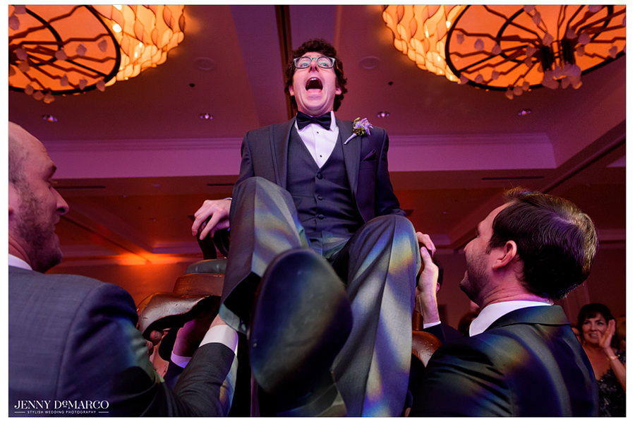 The groom is raised up on his chair by his guests for the hora.