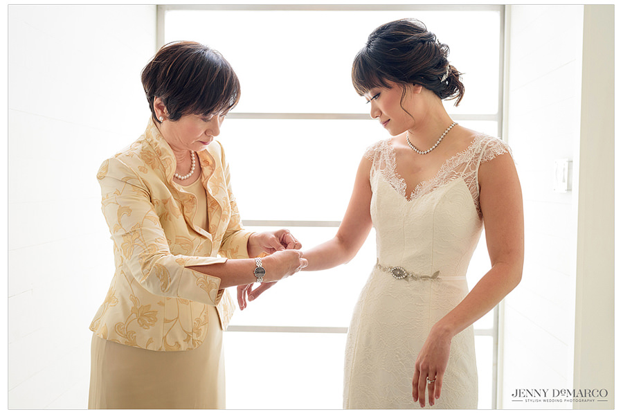 The mother of the bride puts jewelry on her daughter in preparation for the ceremony.
