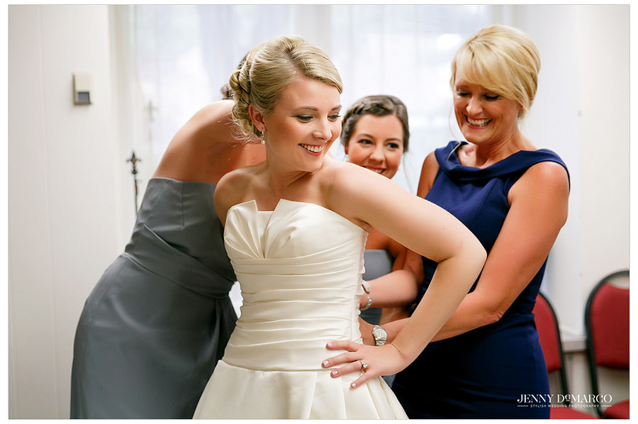 Mother of Bride helps her daughter into her wedding dress
