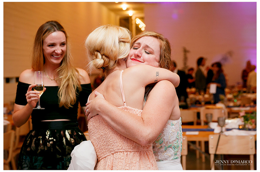 Bride and friend hug at her wedding reception