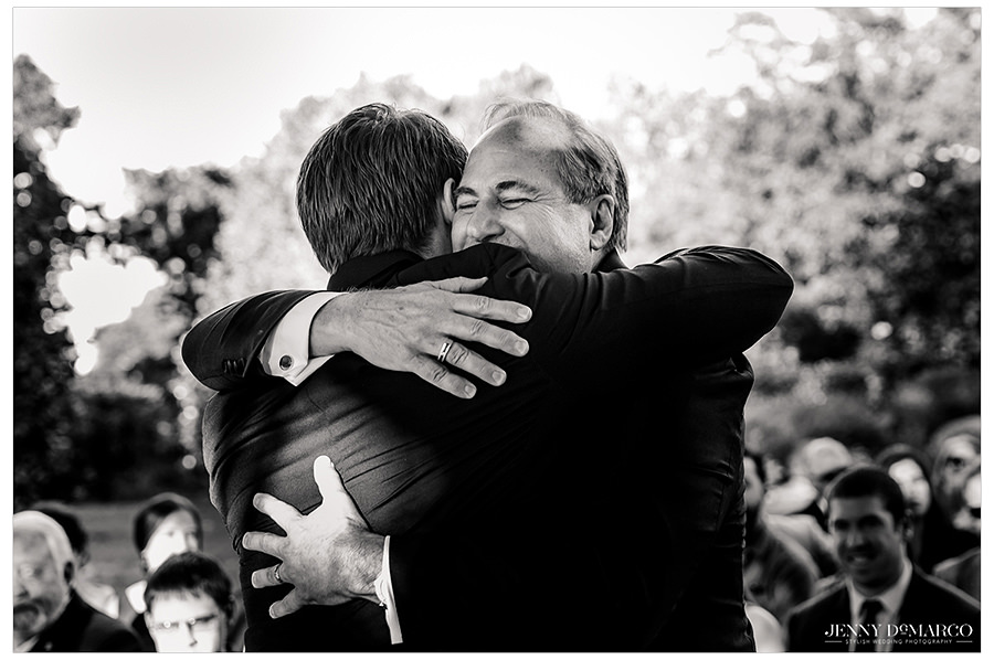the father of the groom hugs his son in a touching shot