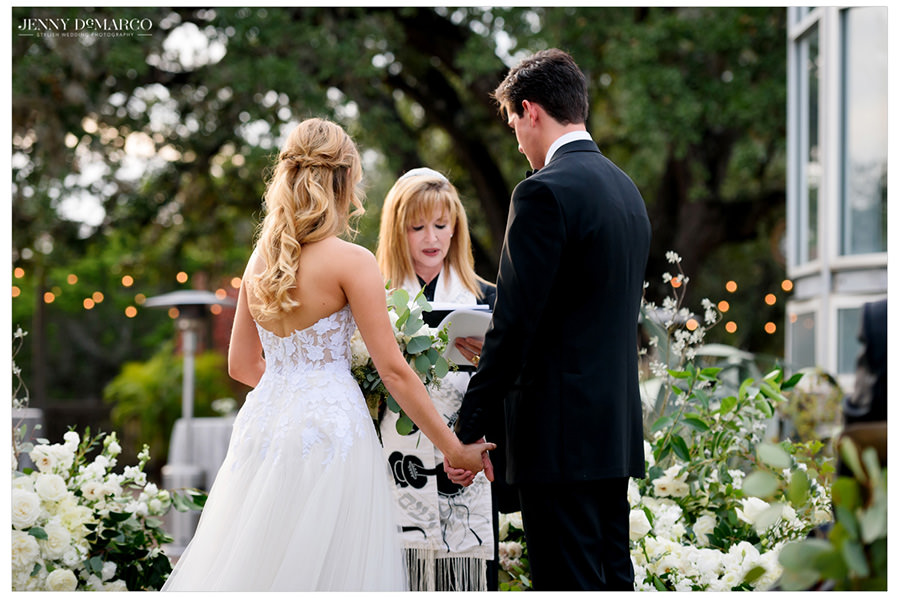 bride and groom hold hands while the officiant speaks
