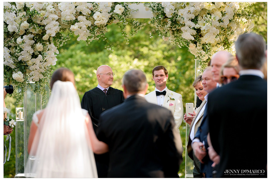 Groom looks longingly at his bride as she walks down the aisle.