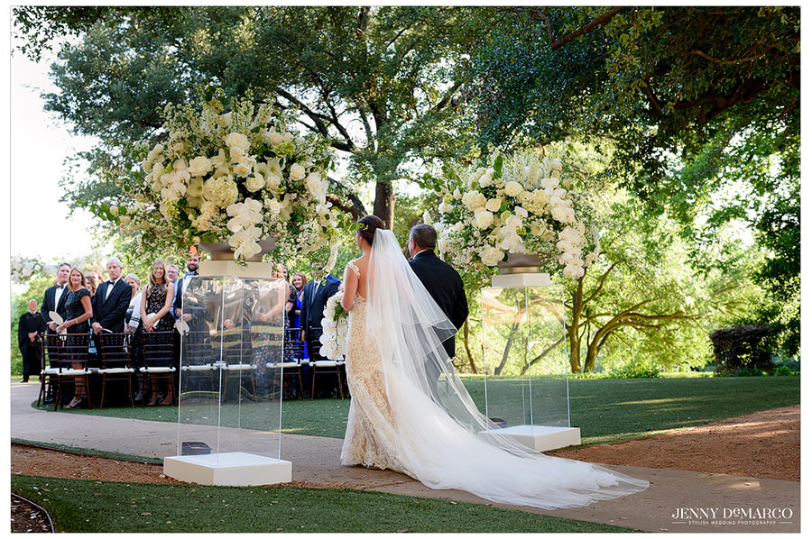 Bride's veil trails behind her as she walks toward her fiancé.