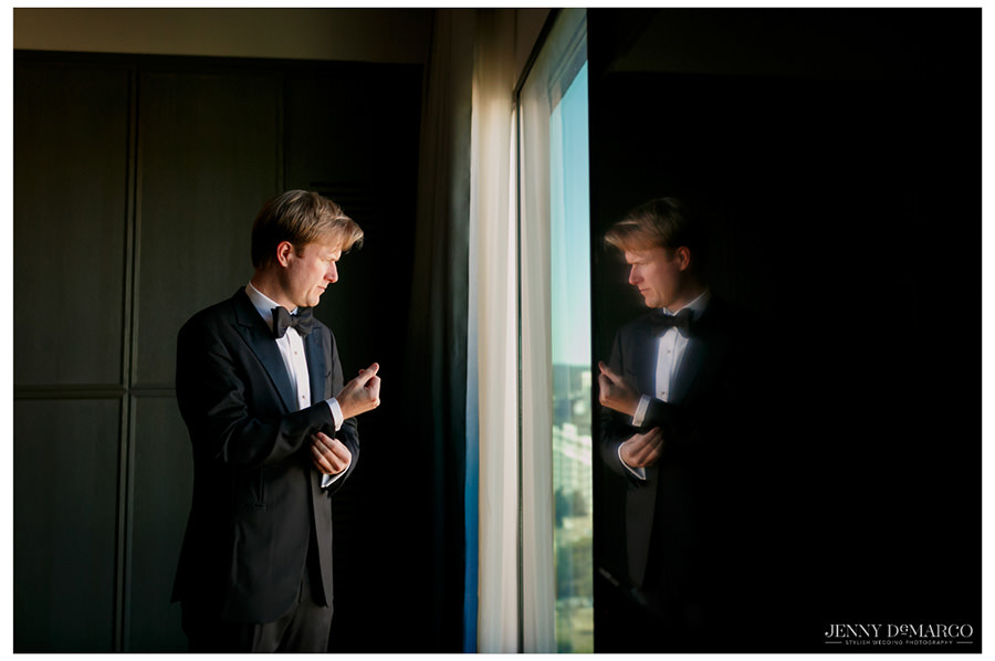 Refection of the groom fixing his cuff links in his hotel room in downtown Austin. 