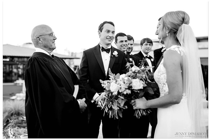 The groom smiling at the bride as she is walked down the aisle. 