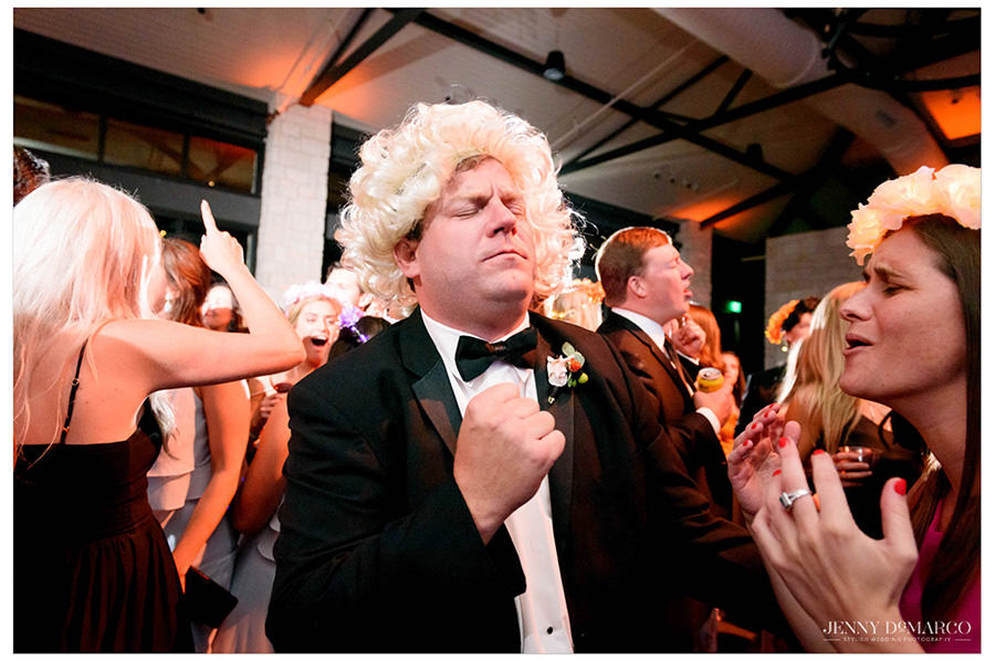 Friends of the couple dancing in the audience with wigs on. 