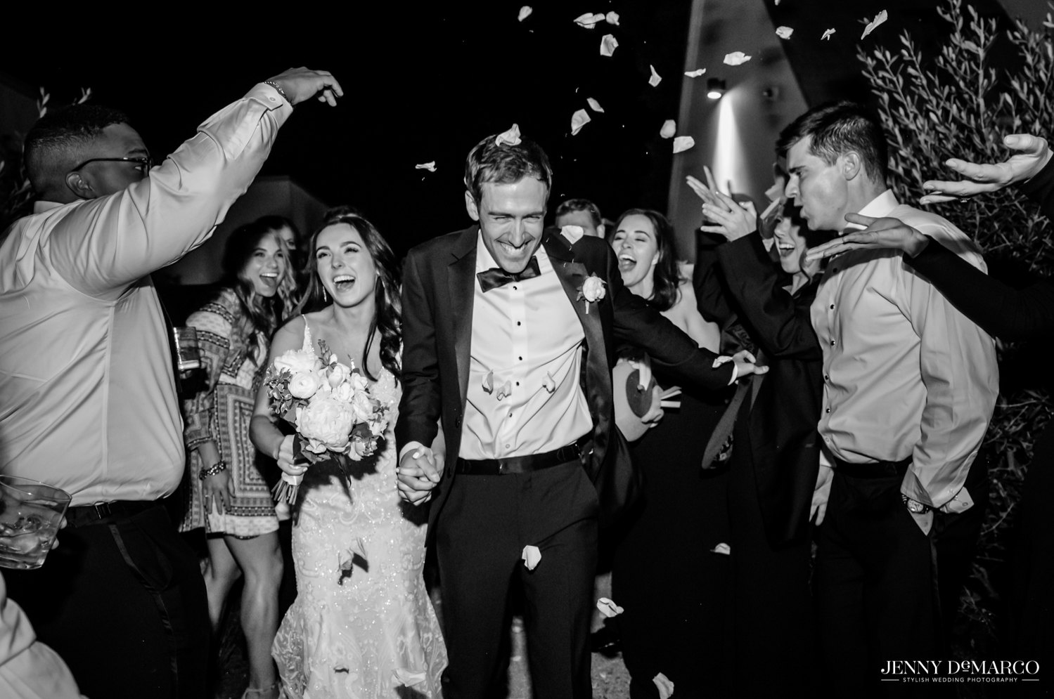 bride and groom exiting as guests throw flower petals on them 