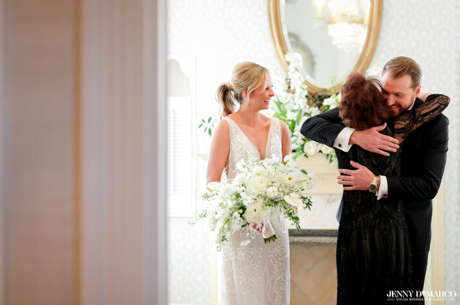 mother of the bride hugging groom as bride smiles at them