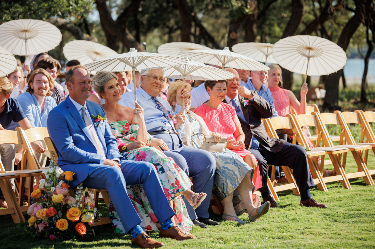 wedding guests during the ceremony holding parasols 