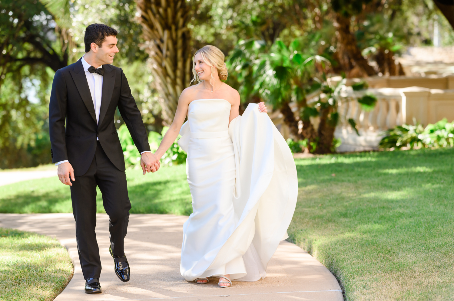 The bride and groom hold hands and walk together, laughing