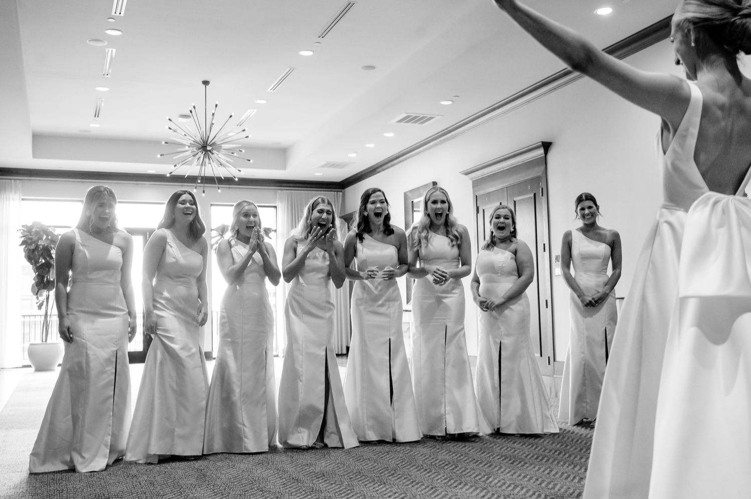 bridesmaids excited as bride shows them her in her wedding dress