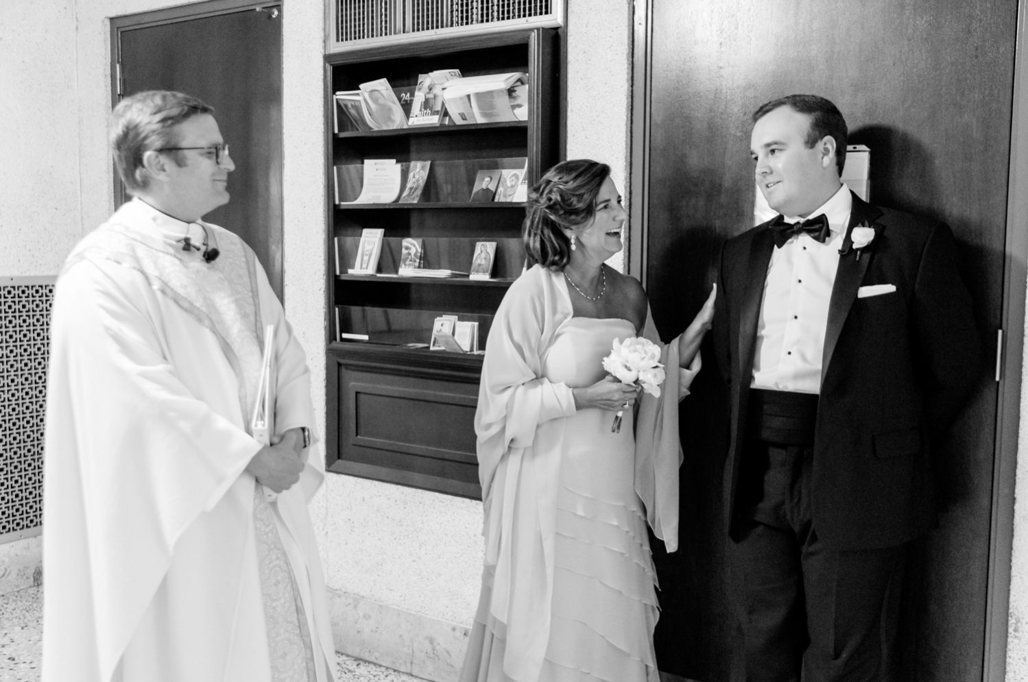 mother of groom talking to her son before wedding ceremony as priest stands by 