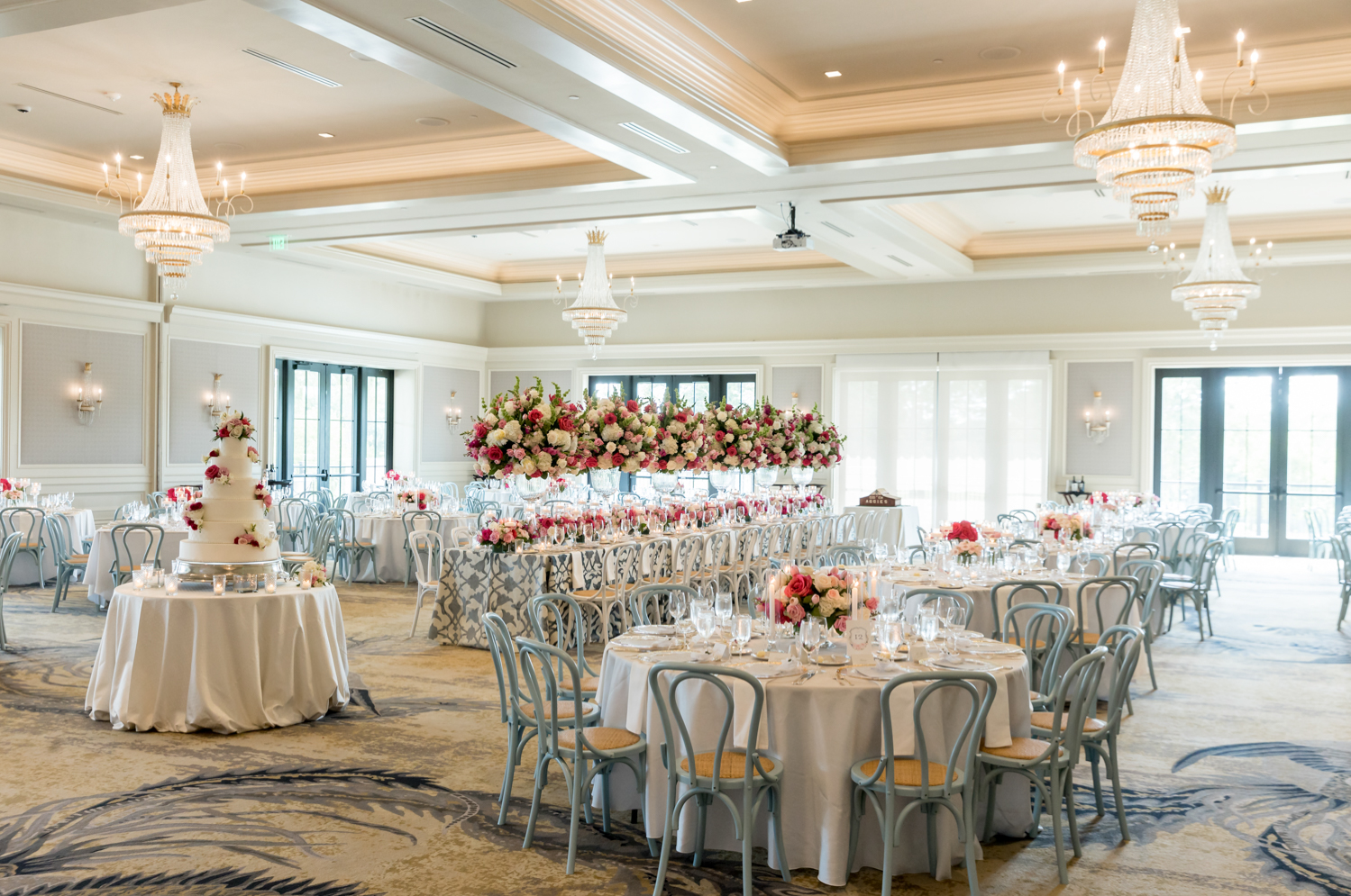 wedding reception room with huge floral centerpieces and wedding cake 