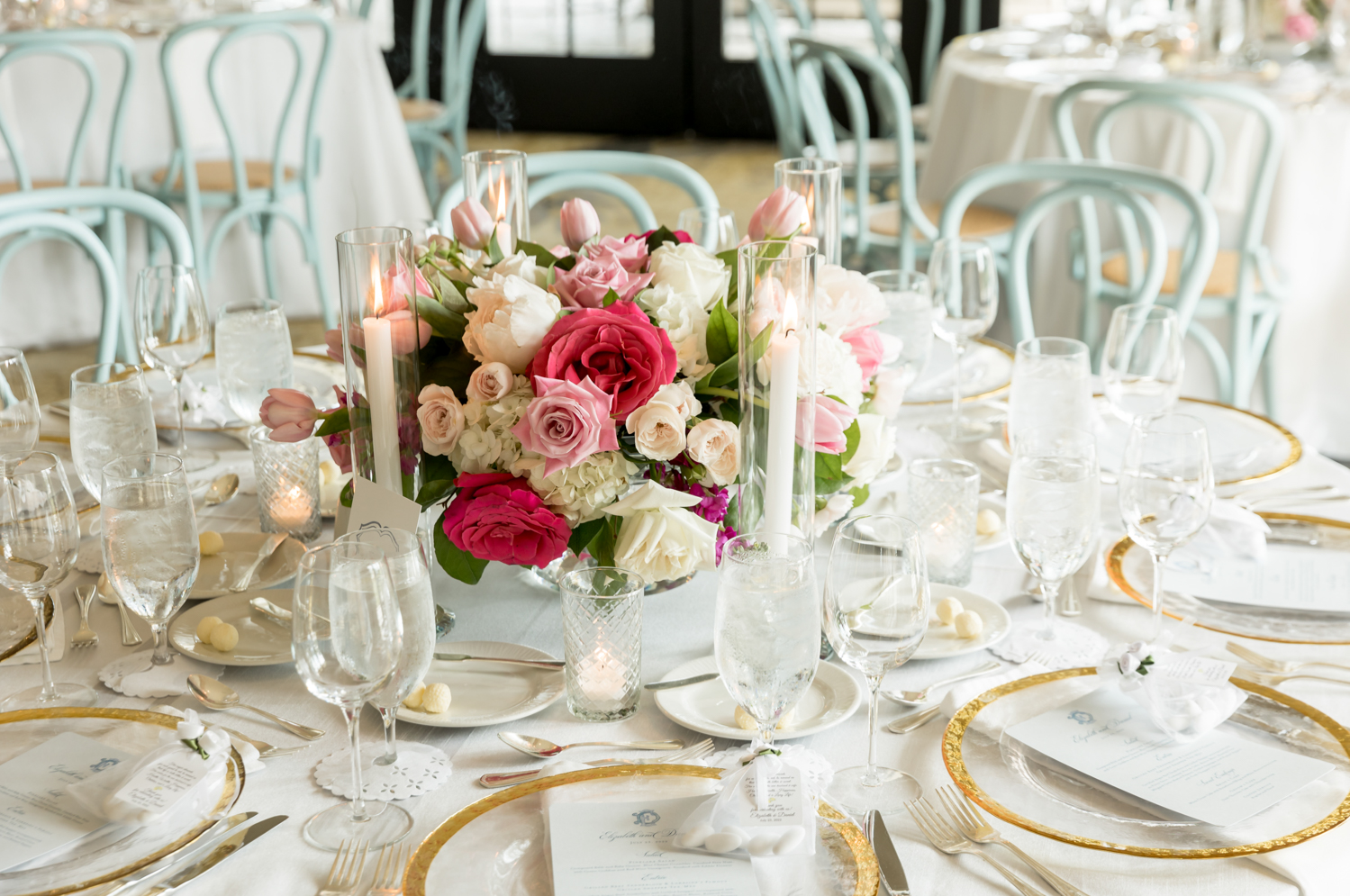 reception table with light blue chairs and pink and white floral centerpiece 