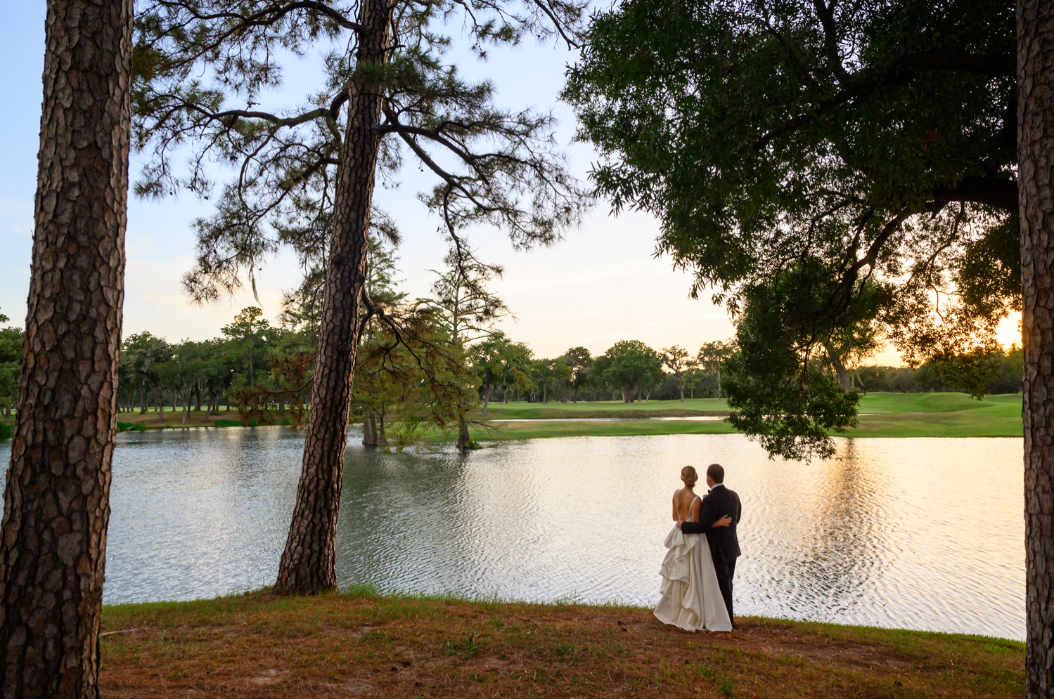 bride and groom looking out over the pond as the sunsets 