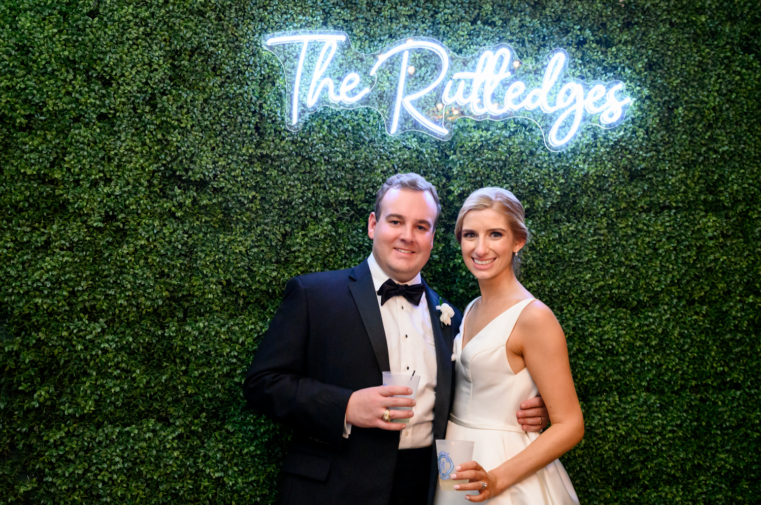 bride and groom posing in front of neon sign 