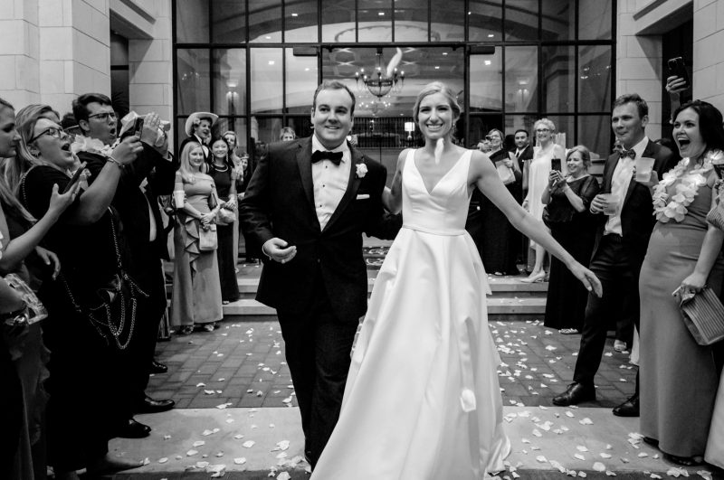 Black-and-white photo of the bride and groom leaving their Lakeside Country Club wedding as guests celebrate