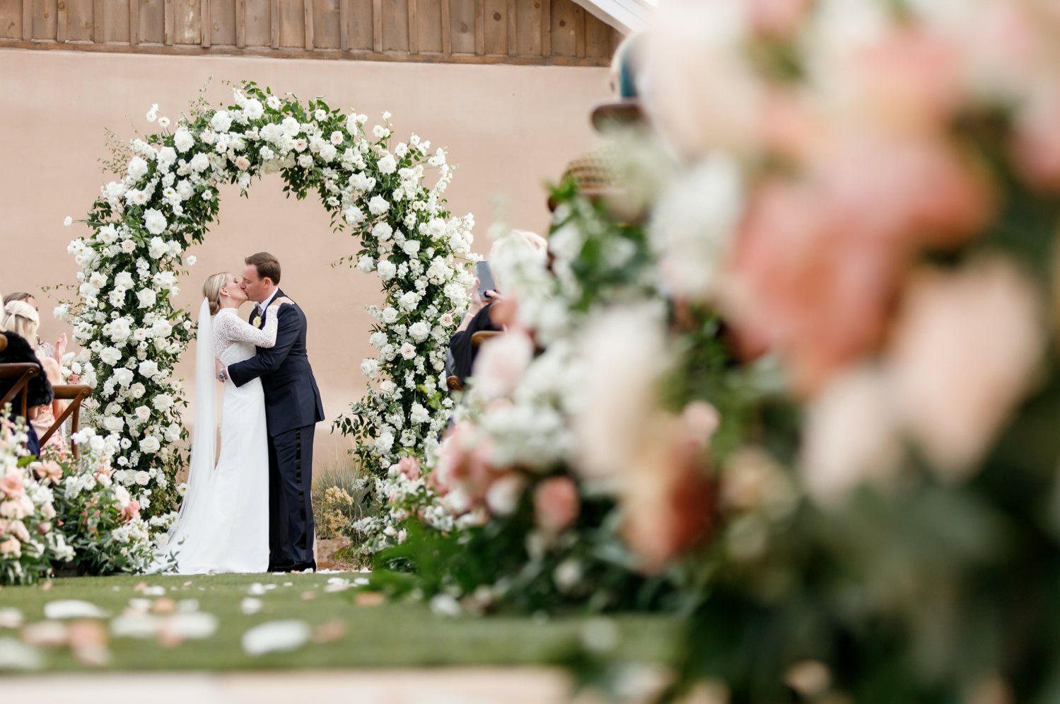 bride and groom kiss under the flower arch