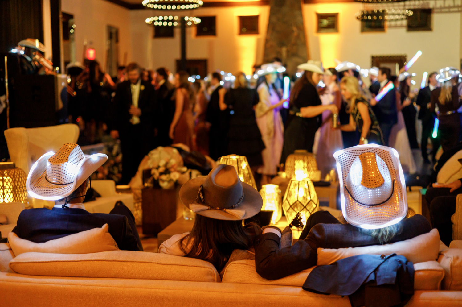guests rest during the reception with light up white cowboy hats on 