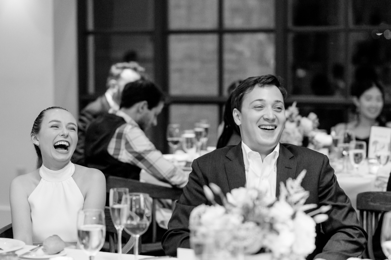 The bride and groom laugh during a rehearsal dinner speech.