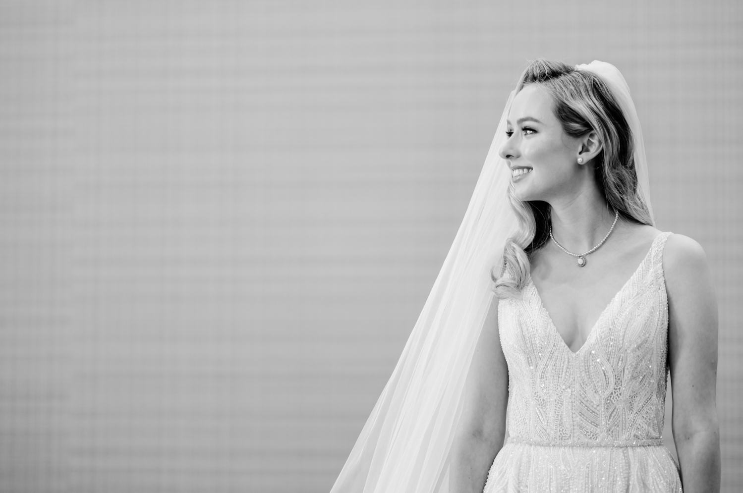 The bride is ready for the day and smiles in her dress and veil