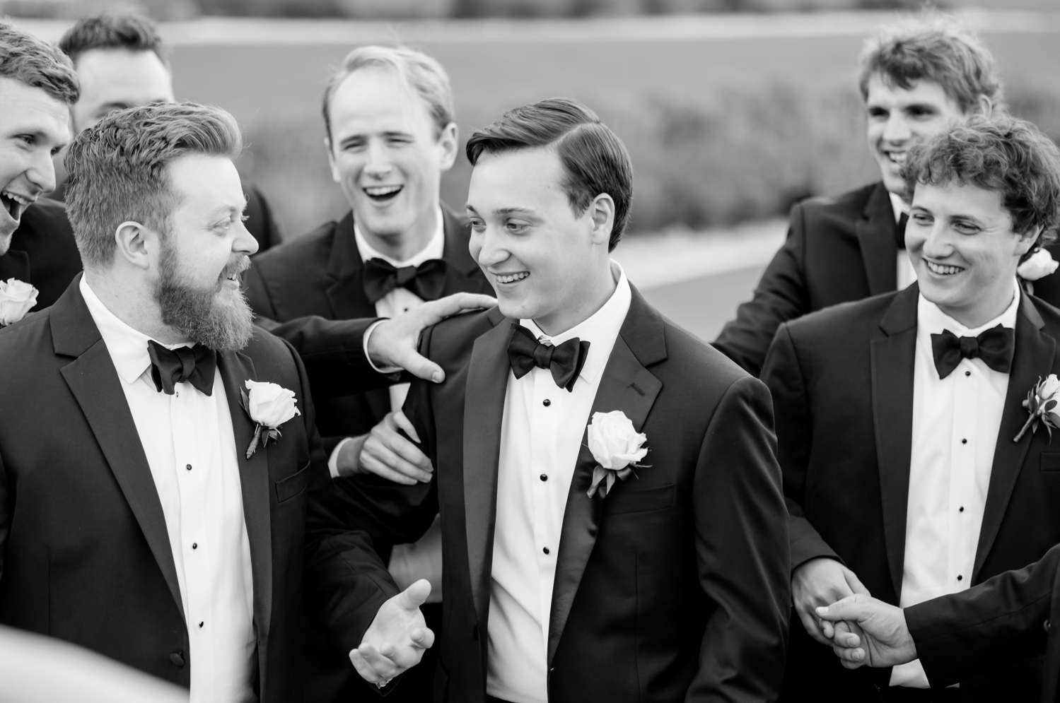 The groomsmen surround the groom and hype him up before the wedding.