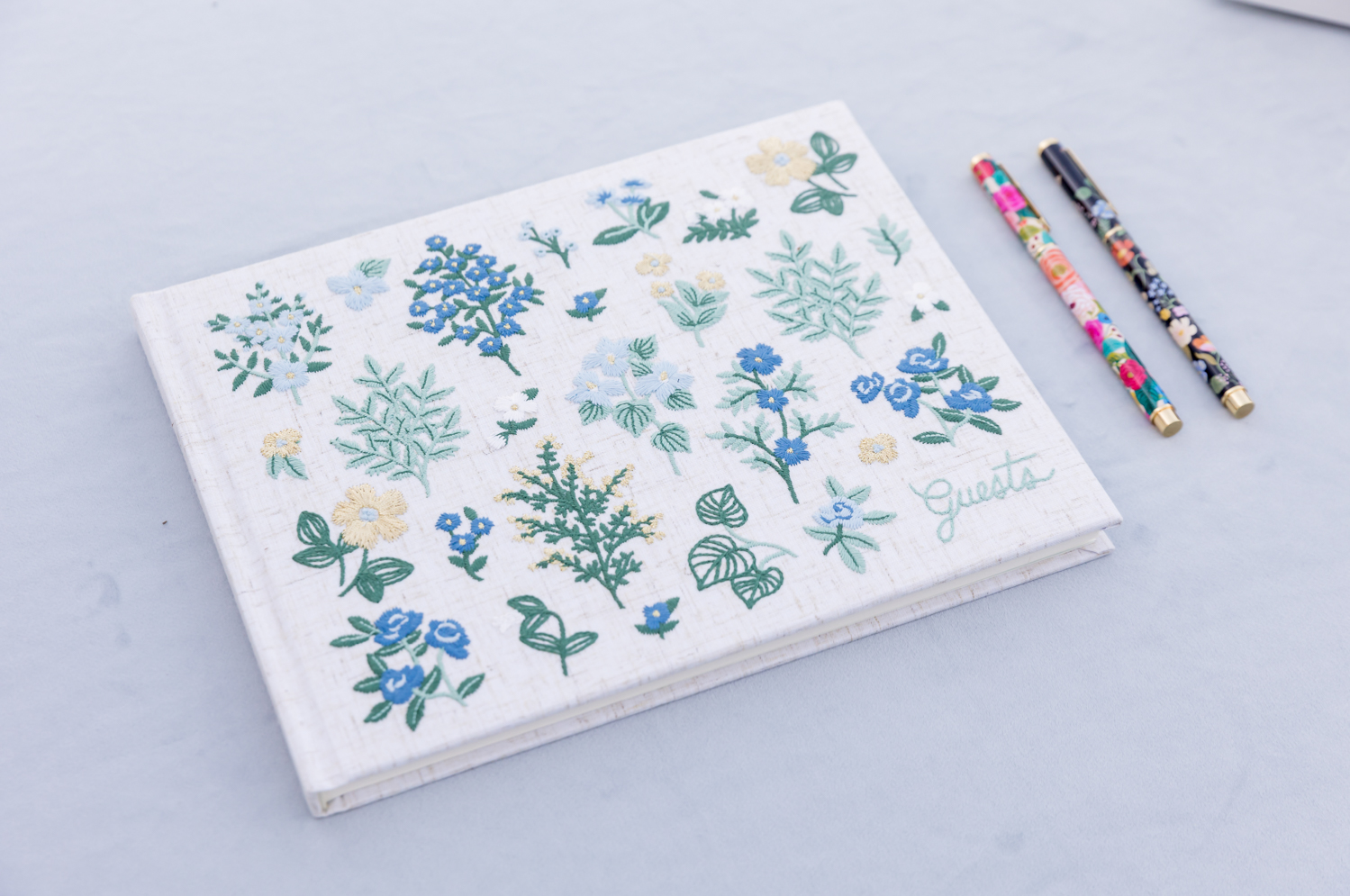 A guest book with blue flowers embroidered on the cover waiting for guests to sign