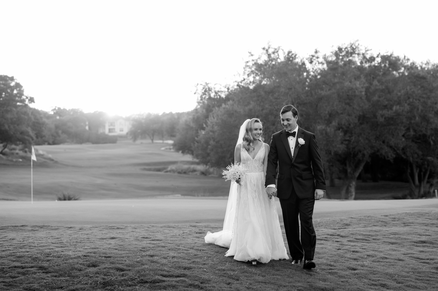 The bride and groom hold hands and walk on the Omni Barton Creek golf course together